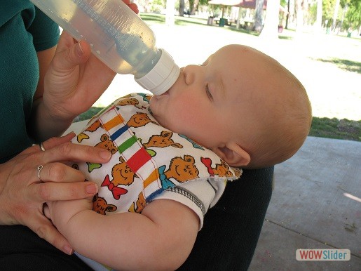 a mother is feeding her baby a bottle